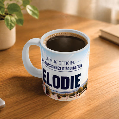 Café fumant dans le mug équitation posé sur un bureau en bois : la phrase « Le mug officiel des passionnés d'équitation » et son prénom en grandes capitales, mug livré chez vous (exemple)