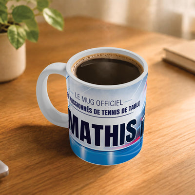 Exemple d'usage : le mug tennis de table rempli de café sur une table en bois ; 330 ml de céramique blanche, votre prénom imprimé sous le titre, livré à domicile (exemple)