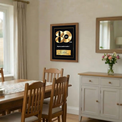 Disque d'or des 80 ans en cadre bois foncé accroché dans une salle à manger ; prénom au centre du disque, signature et message au choix, livré chez vous (exemple)