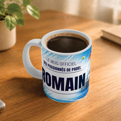 Exemple d'usage : le mug padel rempli de café sur une table en bois ; 330 ml de céramique blanche, votre prénom imprimé sous le titre, livré à domicile (exemple)