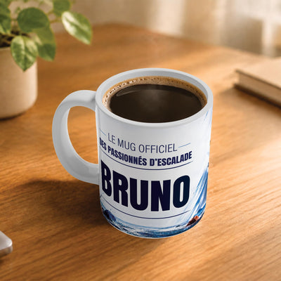 Café fumant dans le mug escalade en salle posé sur un bureau en bois : la phrase « Le mug officiel des passionnés d'escalade » et son prénom en grandes capitales, mug livré chez vous (exemple)