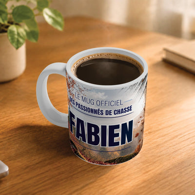 Café fumant dans le mug chasse posé sur un bureau en bois : la phrase « Le mug officiel des passionnés de chasse » et son prénom en grandes capitales, mug livré chez vous (exemple)