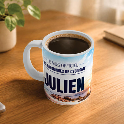 Café fumant dans le mug cyclisme posé sur un bureau en bois : la phrase « Le mug officiel des passionnés de cyclisme » et son prénom en grandes capitales, mug livré chez vous (exemple)