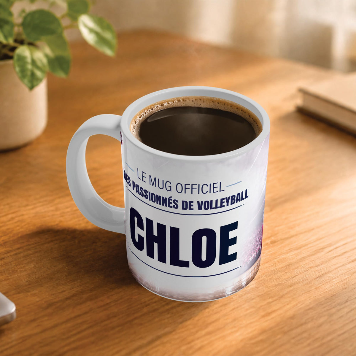 Exemple d'usage : le mug volleyball femme rempli de café sur une table en bois ; 330 ml de céramique blanche, votre prénom imprimé sous le titre, livré à domicile (exemple)