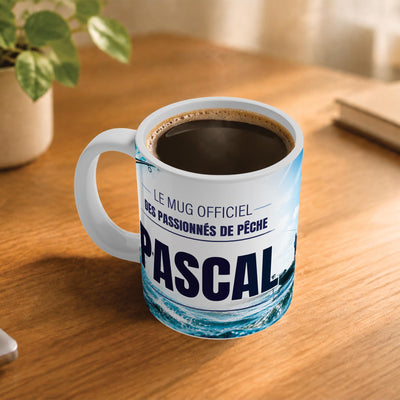 Exemple d'usage : le mug pêche rempli de café sur une table en bois ; 330 ml de céramique blanche, votre prénom imprimé sous le titre, livré à domicile (exemple)