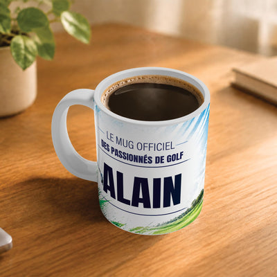Café fumant dans le mug golf posé sur un bureau en bois : la phrase « Le mug officiel des passionnés de golf » et son prénom en grandes capitales, mug livré chez vous (exemple)