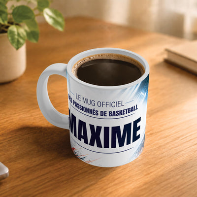 Café fumant dans le mug basket posé sur un bureau en bois : la phrase « Le mug officiel des passionnés de basketball » et son prénom en grandes capitales, mug livré chez vous (exemple)