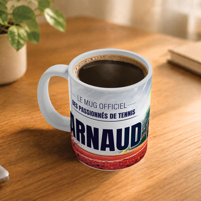 Exemple d'usage : le mug tennis rempli de café sur une table en bois ; 330 ml de céramique blanche, votre prénom imprimé sous le titre, livré à domicile (exemple)