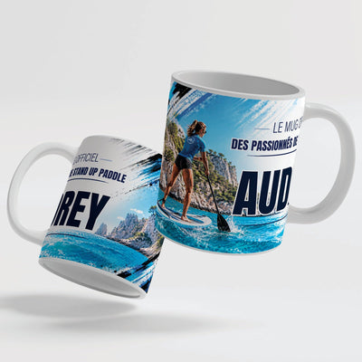 Deux faces du mug stand up paddle femme : le décor continue d'une face à l'autre, prénom au centre ; mug blanc, anse et intérieur colorés ou version magique au choix, livré chez vous (exemple)