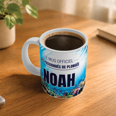 Exemple d'usage : le mug plongée sous-marine rempli de café sur une table en bois ; 330 ml de céramique blanche, votre prénom imprimé sous le titre, livré à domicile (exemple)