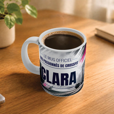 Café fumant dans le mug façon CrossFit posé sur un bureau en bois : la phrase « Le mug officiel » et son prénom en grandes capitales, mug livré chez vous (exemple)